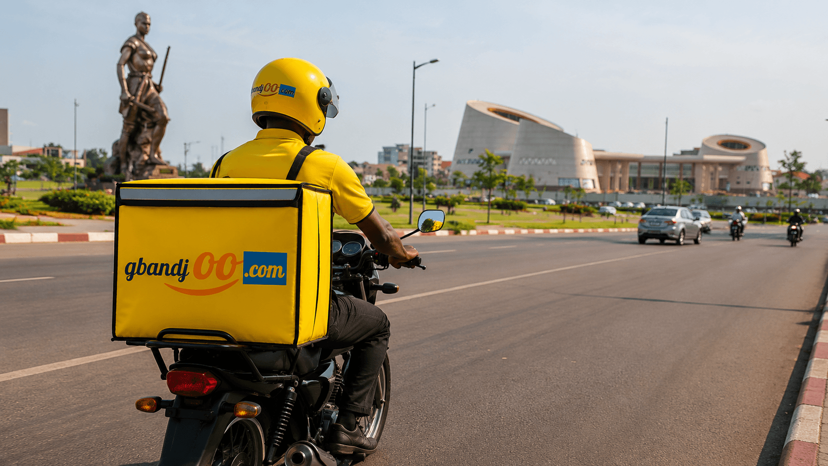 Un livreur gbandjoo en moto avec son sac de livraison jaune devant la Place de l'Amazone à Cotonou